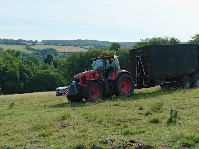 Tractor and high-sided trailer taking timber and waste away from a cleared field